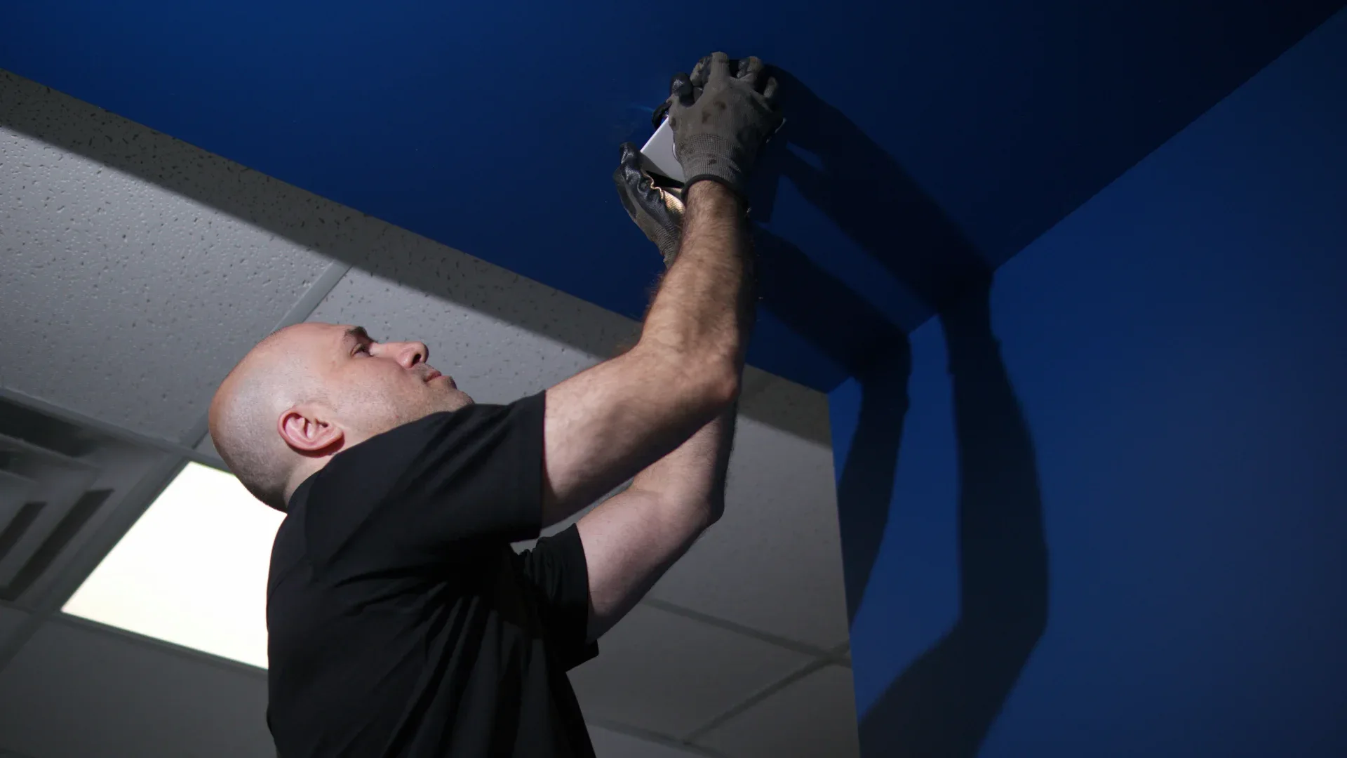 Electrician installing a ceiling fire alarm device