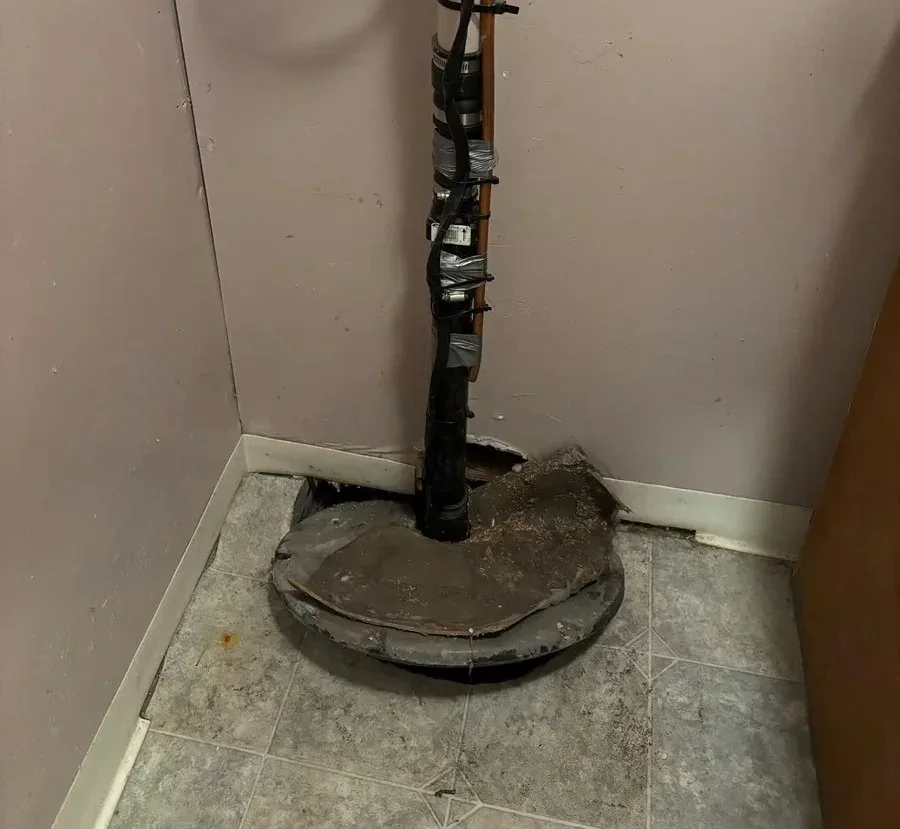 Damaged sump pump basin with an exposed discharge pipe